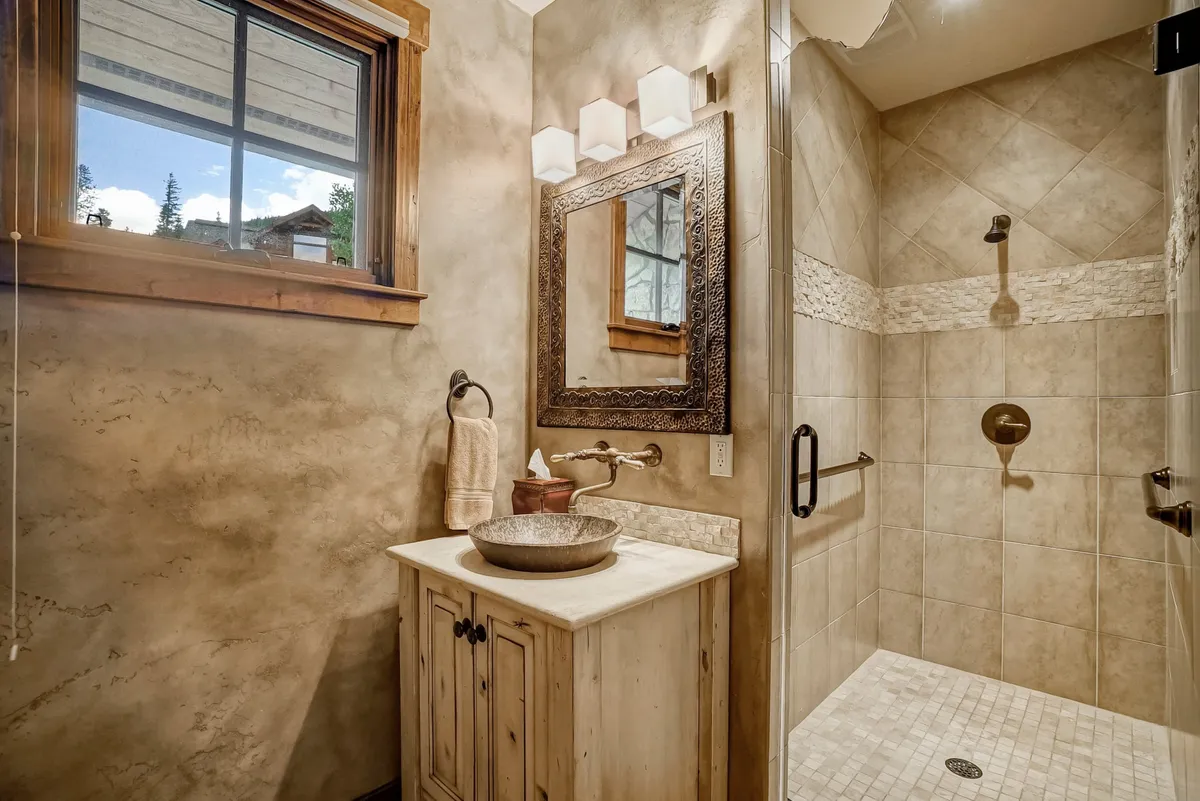 A spa-like bathroom with a striking wooden vanity, decorative mirror, a glass-enclosed shower area, and soft lighting. The calming, contemporary design invites moments of relaxation and self-care in a private setting.