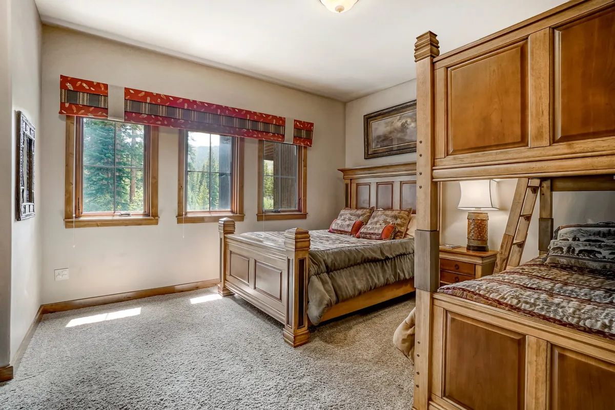 A warm, family-friendly bedroom with a combination of a bunk bed and a main bed, cheerful bedding, sunny windows, and playful artwork. The room exudes a welcoming, cozy vibe that’s perfect for children and families to bond and unwind after a day full of adventure.