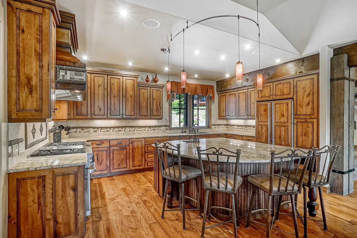 A gourmet kitchen with a large central island, custom wooden cabinetry, and stylish pendant lighting. The layout is perfect for cooking, entertaining guests, or gathering for family recipes, and the high-end finishes create a chef’s dream environment.